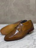 Pair of brown leather dress shoes on a marble surface with a neutral background