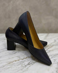 Pair of black high-heeled shoes on a marble surface with a neutral background