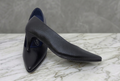 Black high-heeled shoes on a marble surface with photo editing software interface.